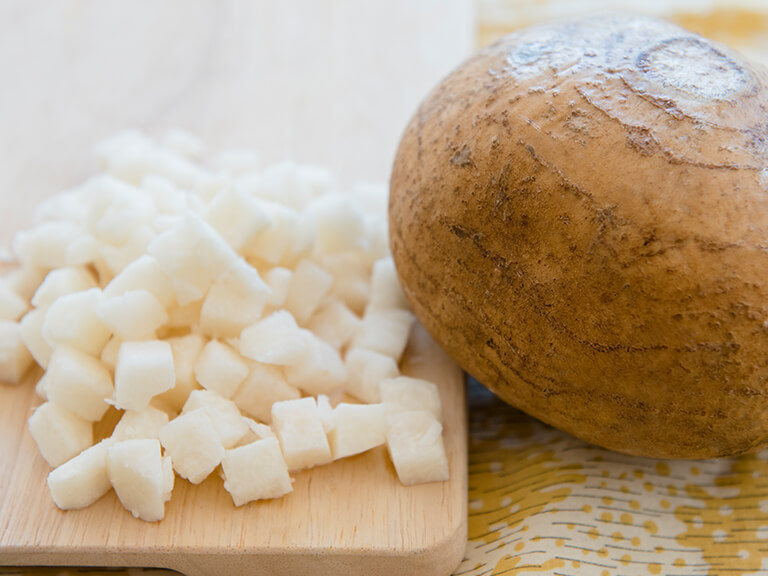 Photo of Jicama root vegetable next diced Jicama on cutting board