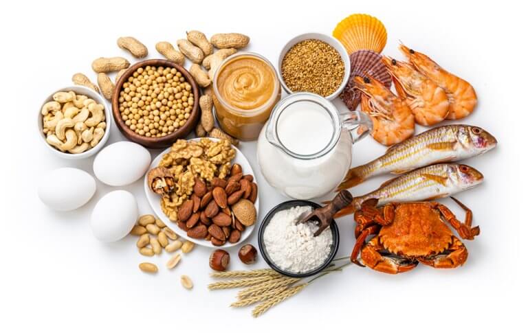 Photo of foods causing allergic reaction. Foods include a variety of nuts, peanut butter, milk, eggs, various grains, fish, shel fish and crab.
